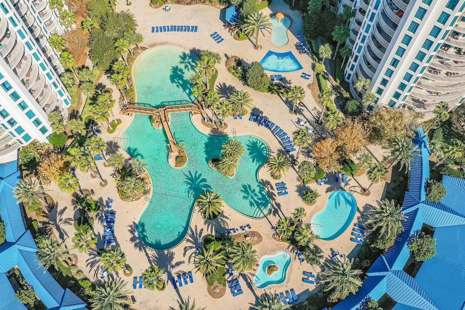 Aerial view of the resort's expansive pool complex surrounded by high-rise buildings and tropical landscaping.