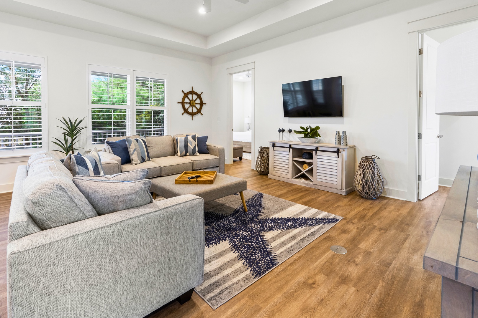 Sink into plush coastal-inspired seating where nautical touches and warm wood floors create your perfect retreat for movie nights and relaxation.