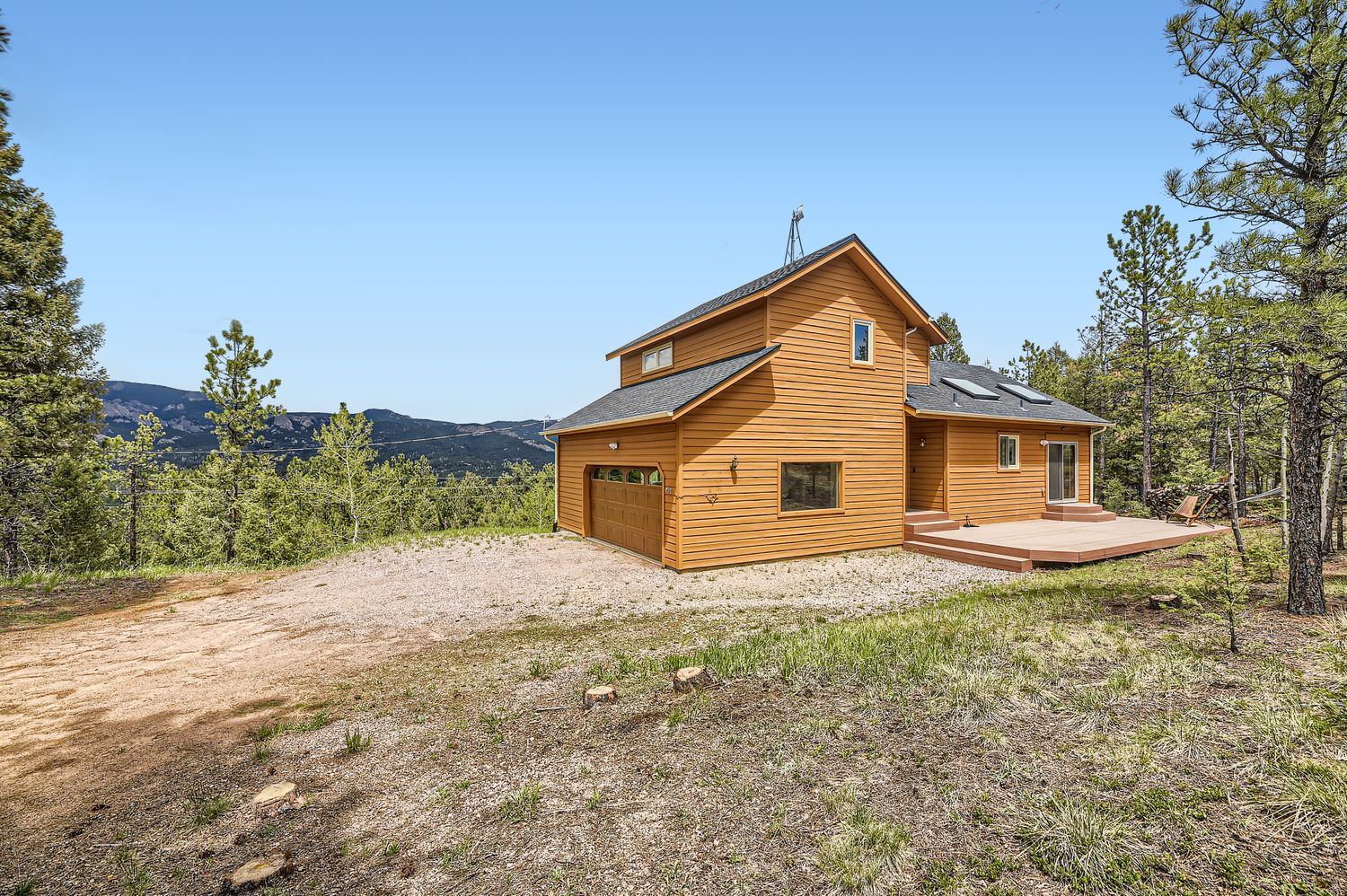 Modern wooden cabin nestled among trees with mountain backdrop and spacious outdoor area for memorable stays.