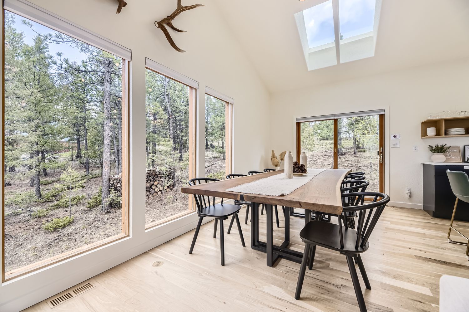 Gather around your stunning dining table surrounded by floor-to-ceiling windows that frame the peaceful forest views.