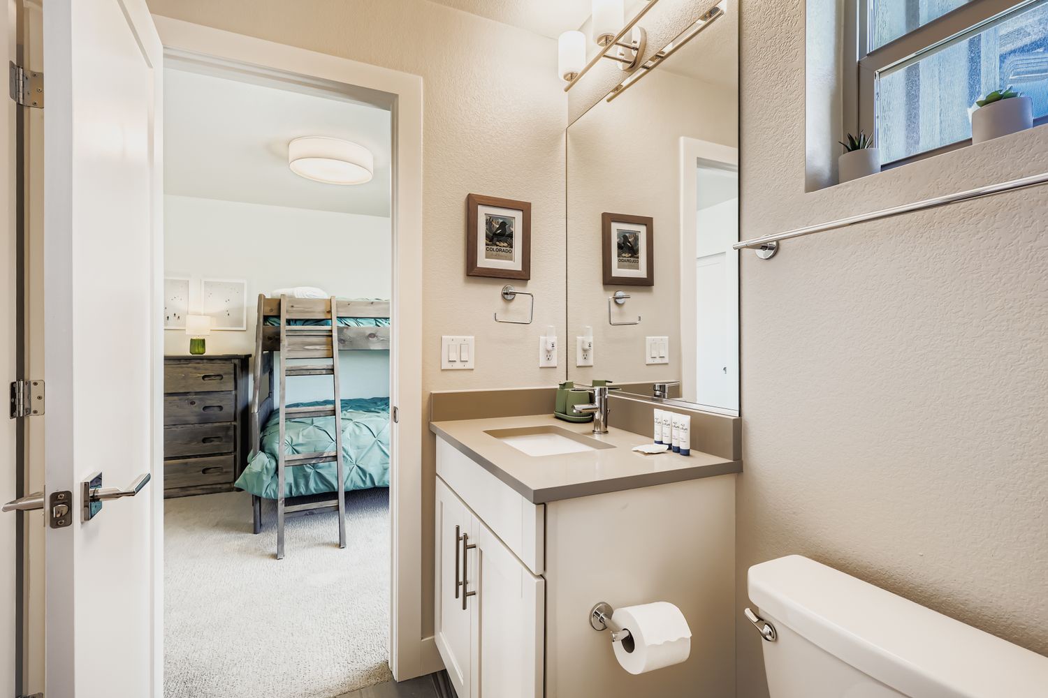 Your private bathroom offers modern amenities with a spacious vanity, while the adjacent bedroom features comfortable bunk beds perfect for families.