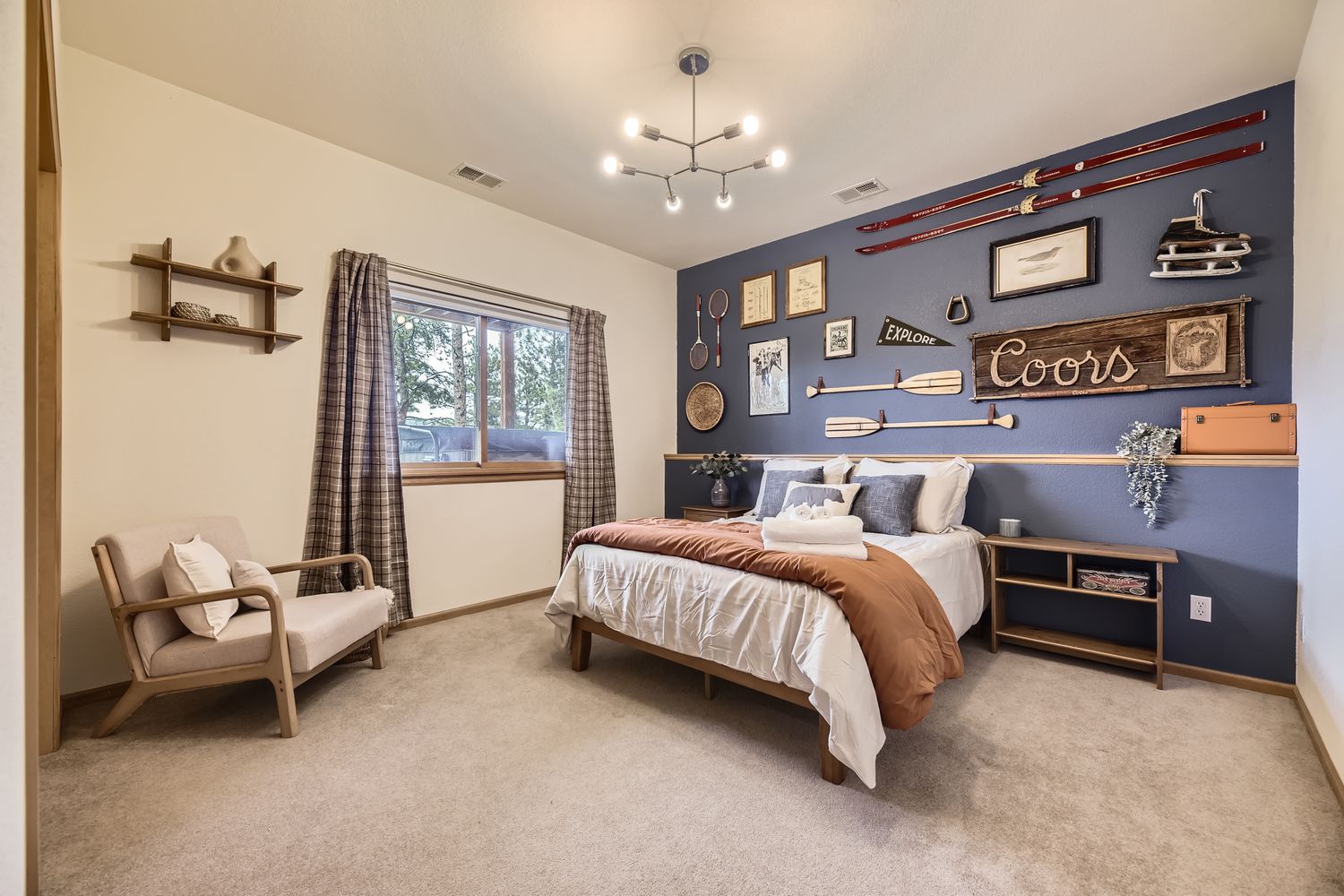 Your cozy bedroom features warm wood tones and rustic charm with a striking navy accent wall adorned with vintage oars and outdoor-themed decor.