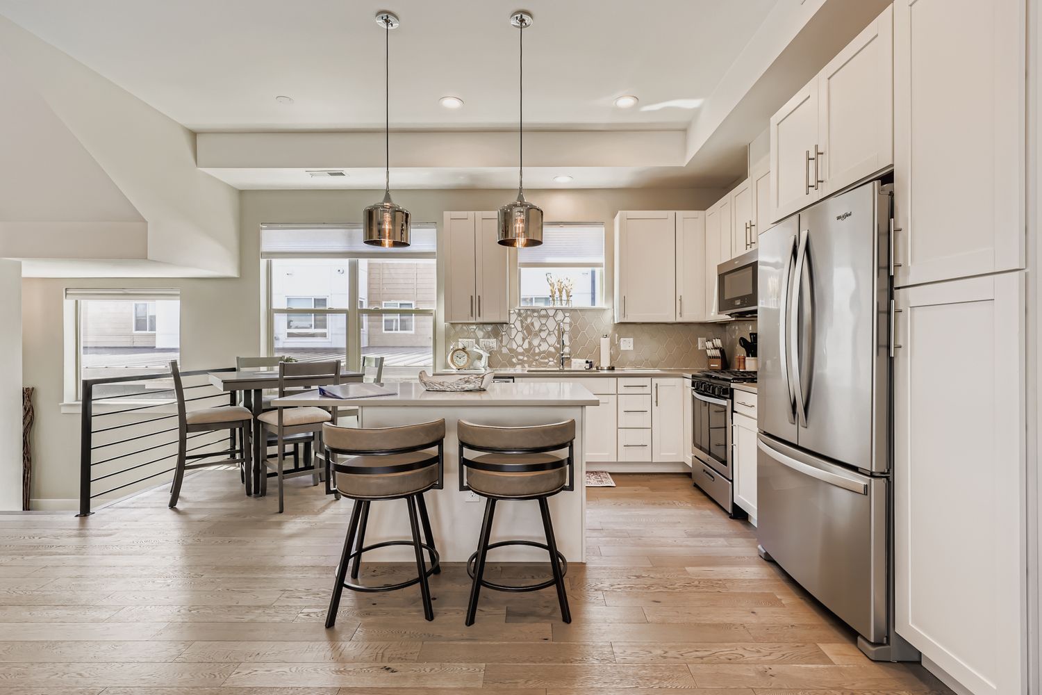 Your sleek modern kitchen features stainless steel appliances, elegant pendant lighting, and a spacious island perfect for morning coffee or evening meals.