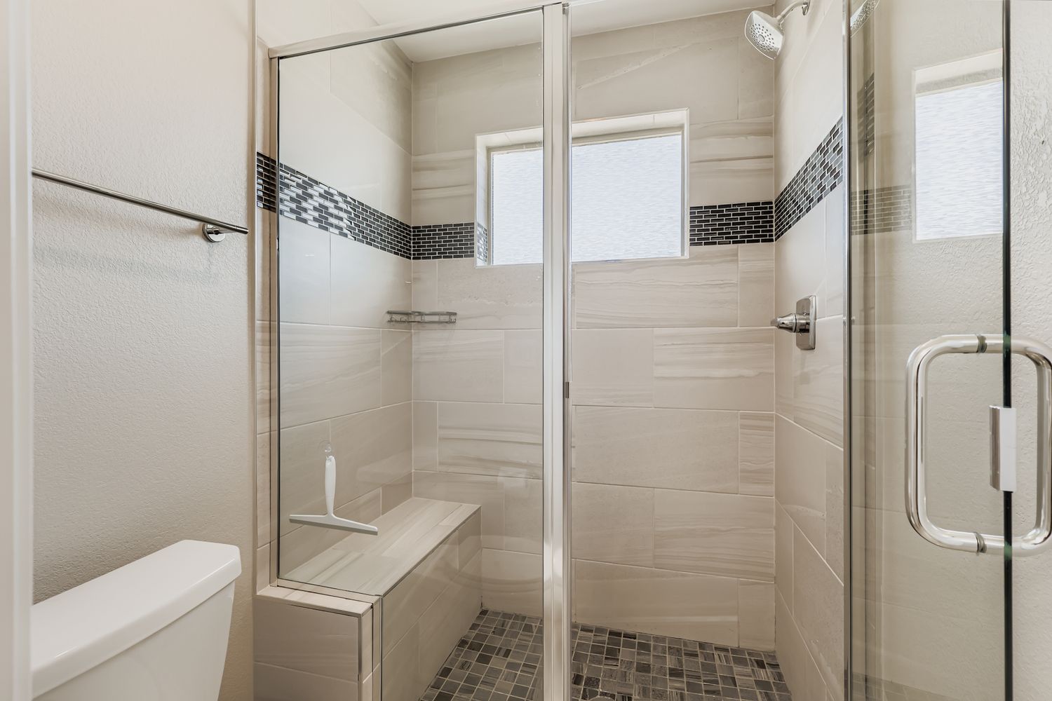 Step into your sleek glass-enclosed shower featuring beautiful tile accents and modern rainfall showerhead for refreshing morning starts.
