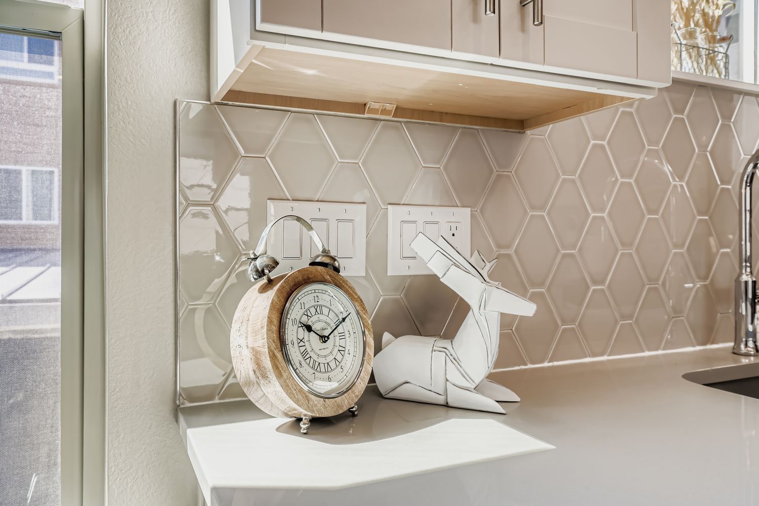 Your stylish kitchen corner features elegant hexagon tile backsplash and charming vintage clock—perfect for morning coffee moments.