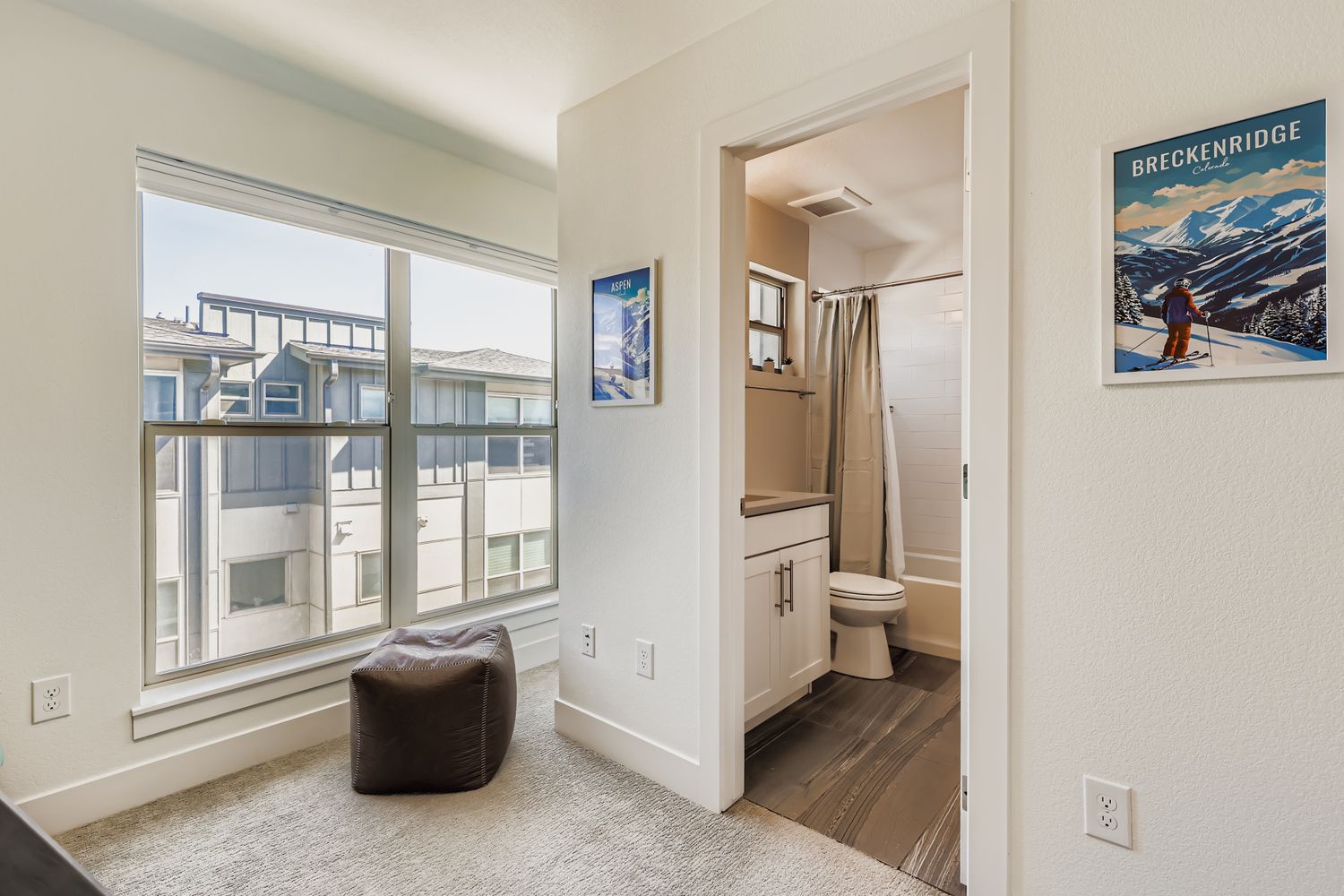 Your cozy reading nook awaits by the window, with mountain artwork inspiring your next adventure and a pristine bathroom just steps away.