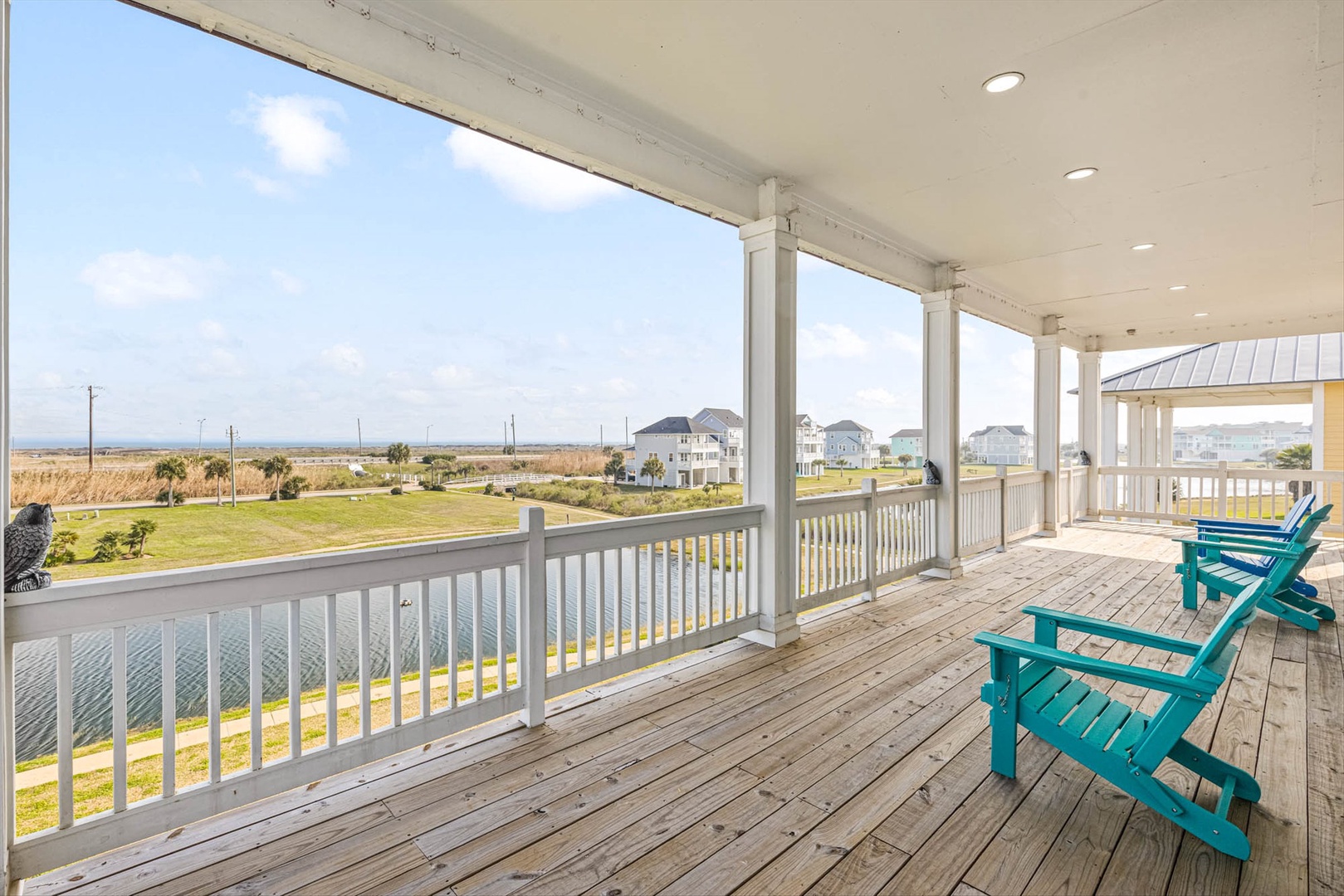 Covered deck with turquoise chairs and coastal views.