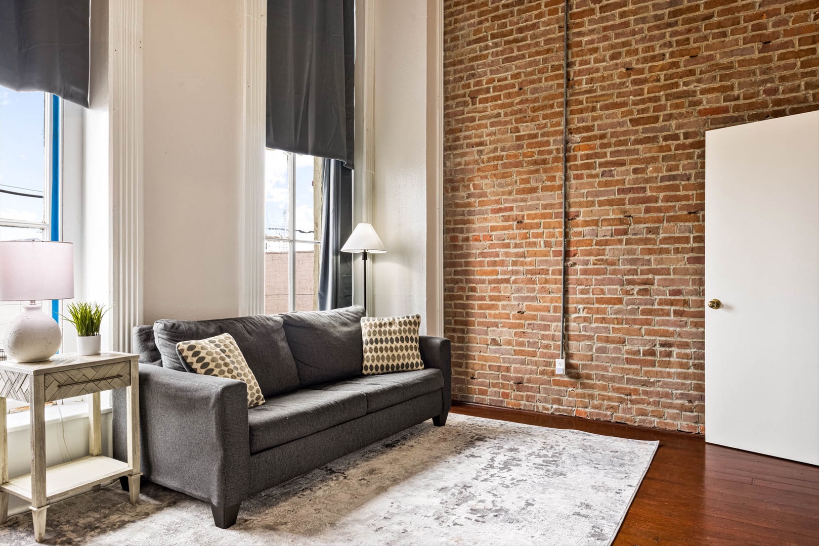 Loft with brick walls, soaring ceilings, and oversized windows.