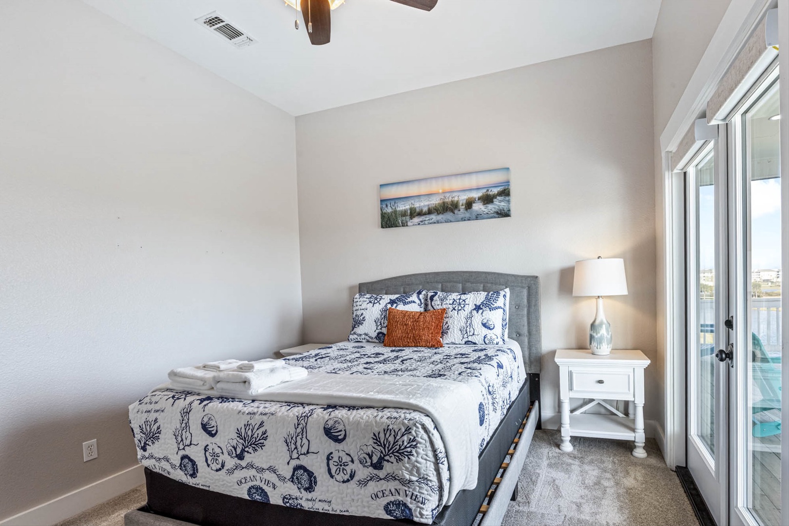 Coastal bedroom with ocean artwork and seaside linens.