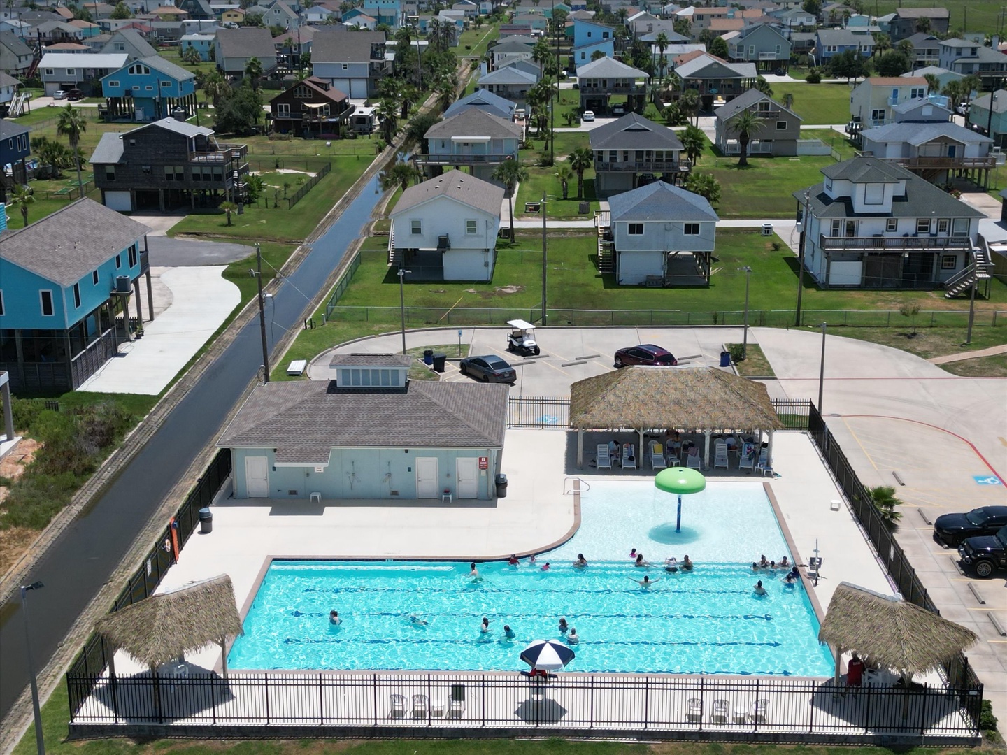 Aerial view of the resort's tropical-style community pool and surrounding residential neighborhood, offering a relaxing recreational centerpiece for the vacation rental area.