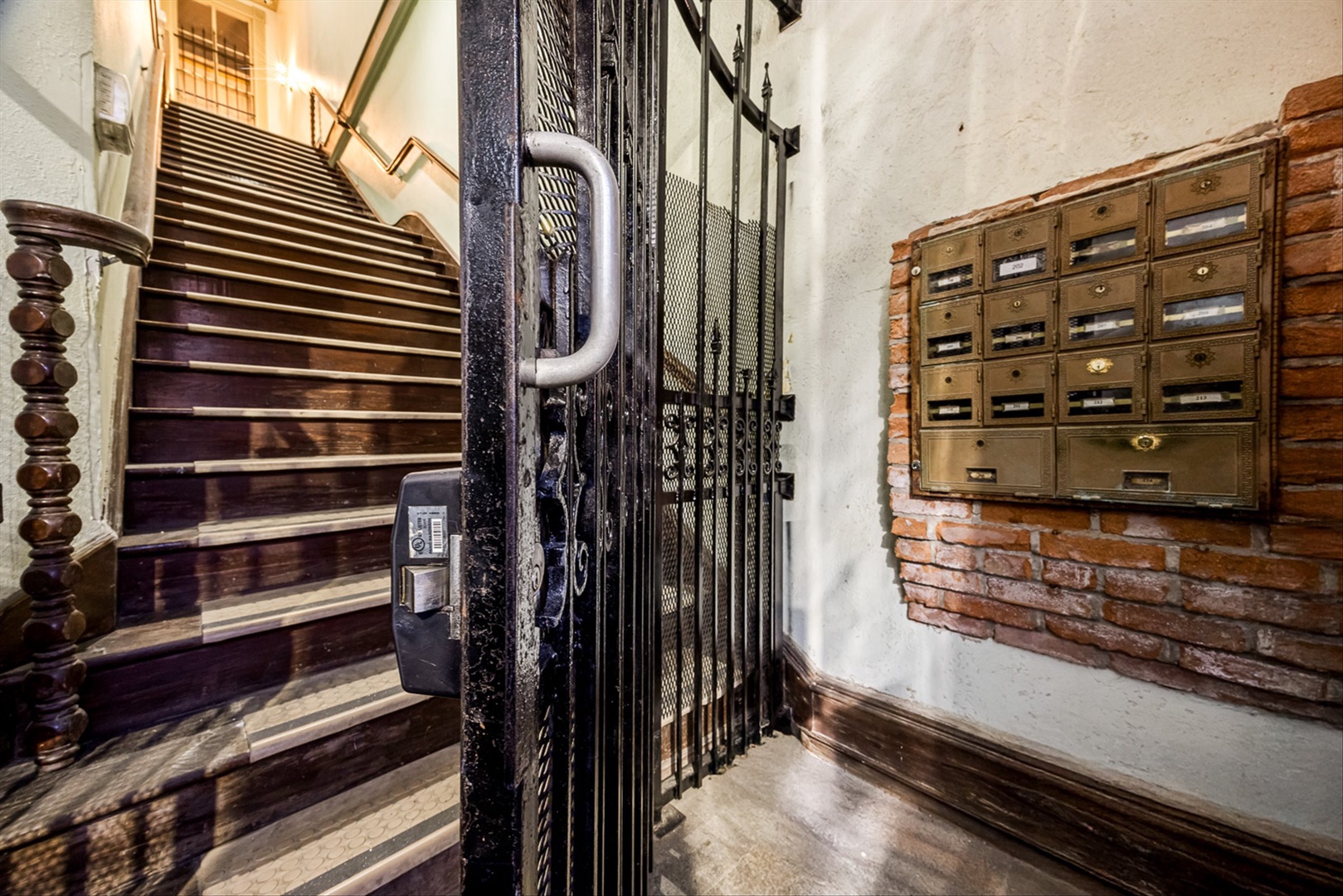 Historic entrance with original brick, vintage mailboxes, stairs.