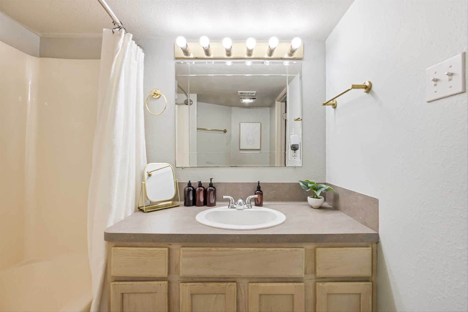 Bright bathroom with warm wood vanity and spa-like touches.