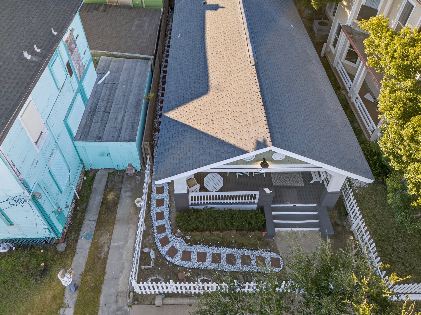 Aerial view of the charming property with curved walkway, surrounded by lush greenery and neighboring homes in peaceful residential area.