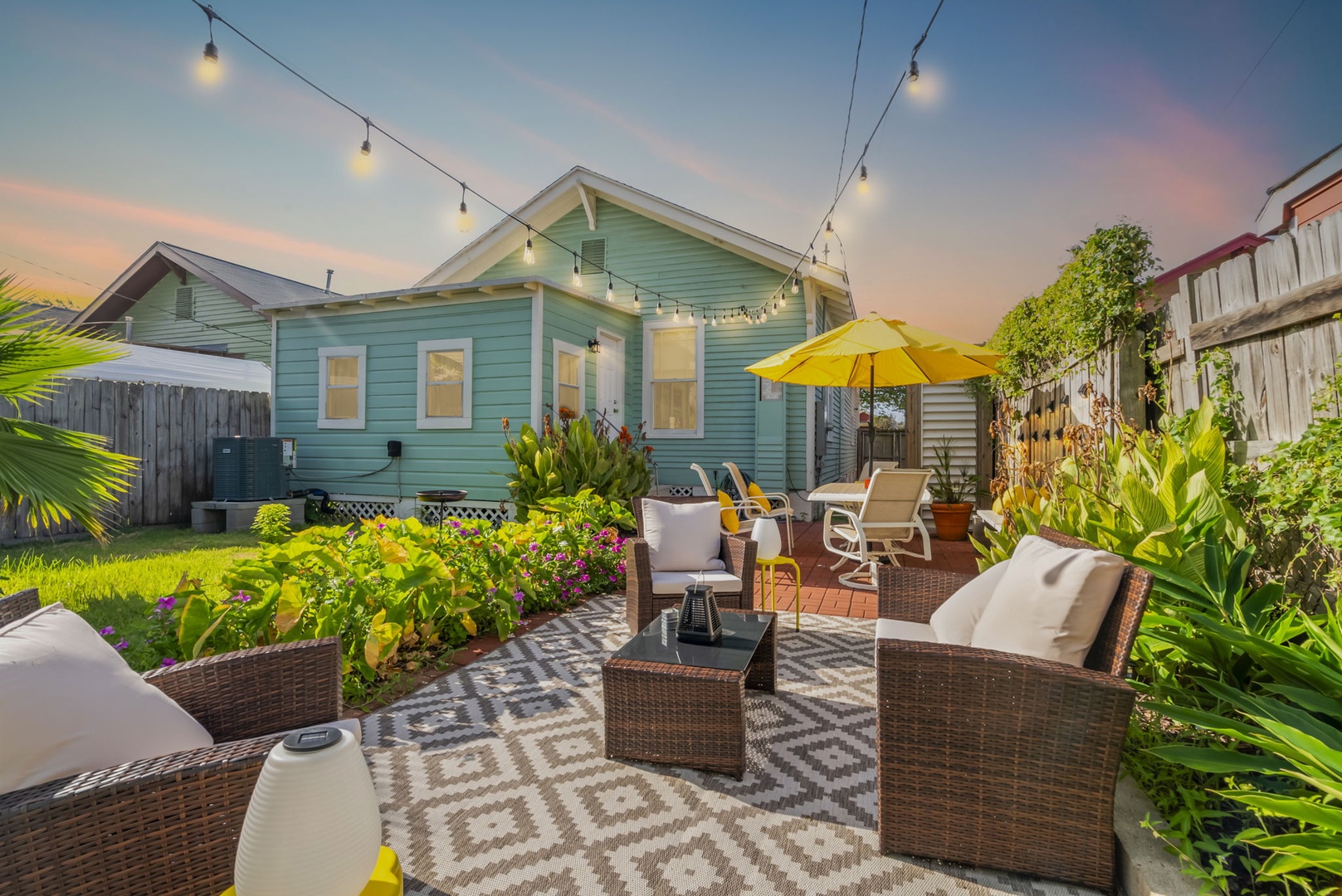 Outdoor oasis with wicker seating and twinkling string lights.