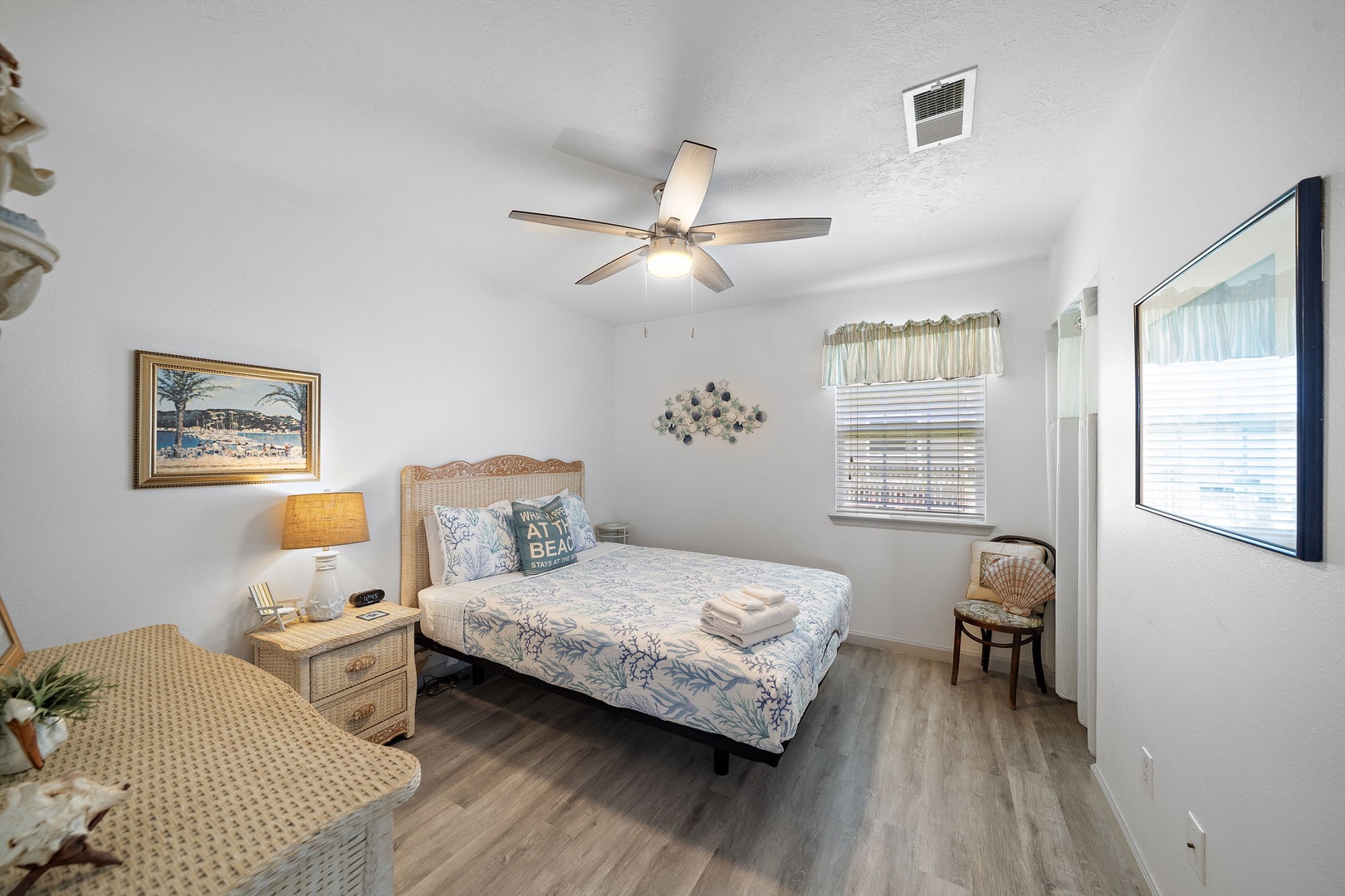 Step into your peaceful coastal retreat off the living room where fresh linens await and gentle breezes from the ceiling fan create the perfect atmosphere for relaxation after your beach adventures.