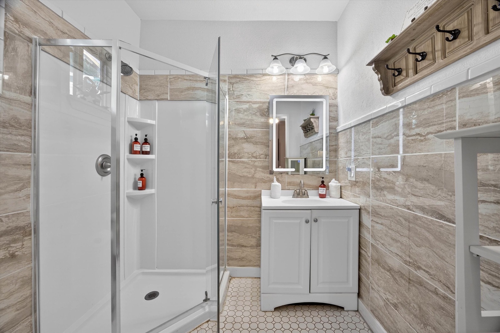 Step into your elegantly designed ensuite bathroom in the primary bedroom featuring beautiful wood-grain tile, modern fixtures, and thoughtful touches that make daily routines feel luxurious.
