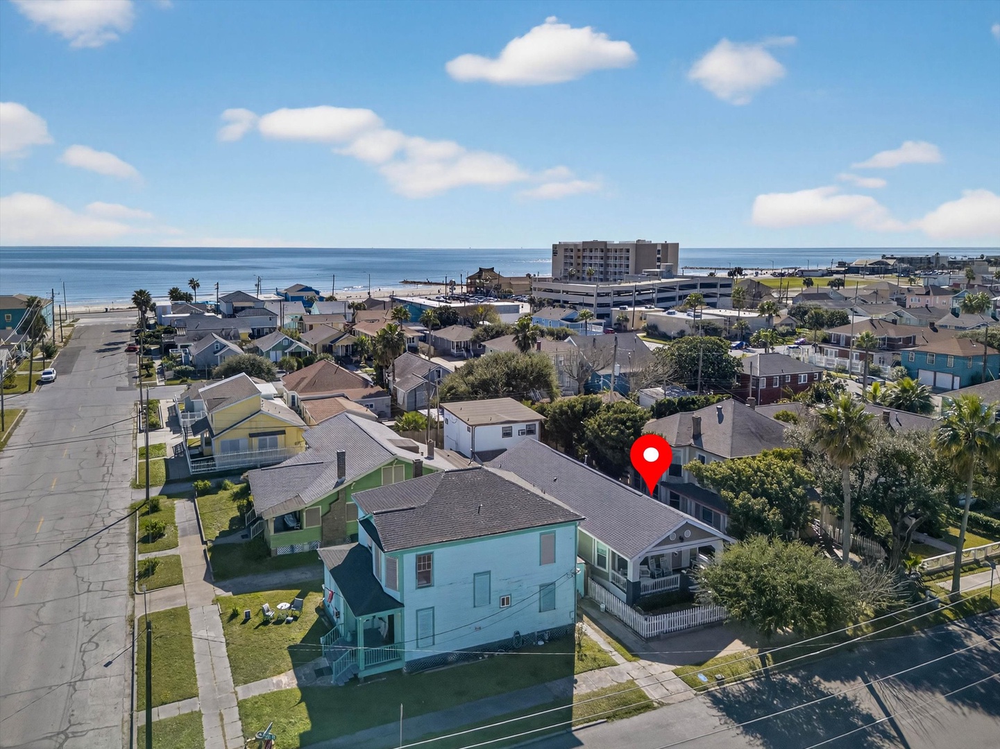 Aerial view of charming beachside neighborhood with colorful homes, mature palm trees, and direct beach access just steps away.