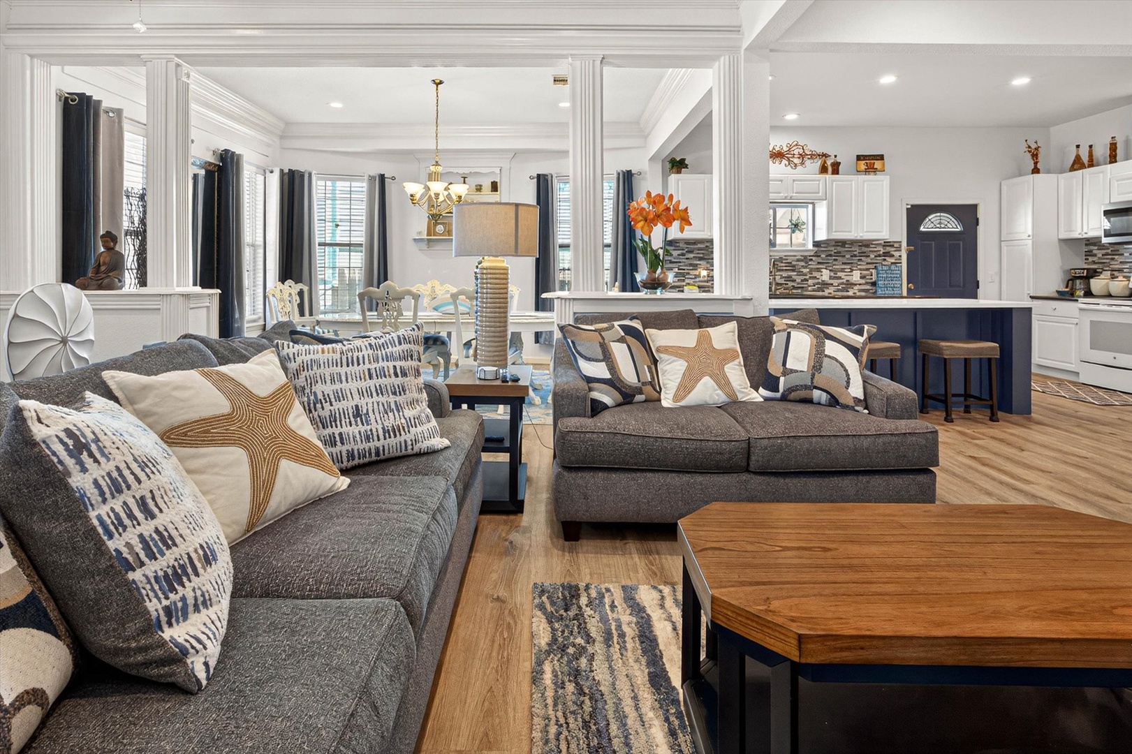 Sink into plush sofas in this elegant open-concept living space, where coastal charm meets modern comfort for perfect relaxation.