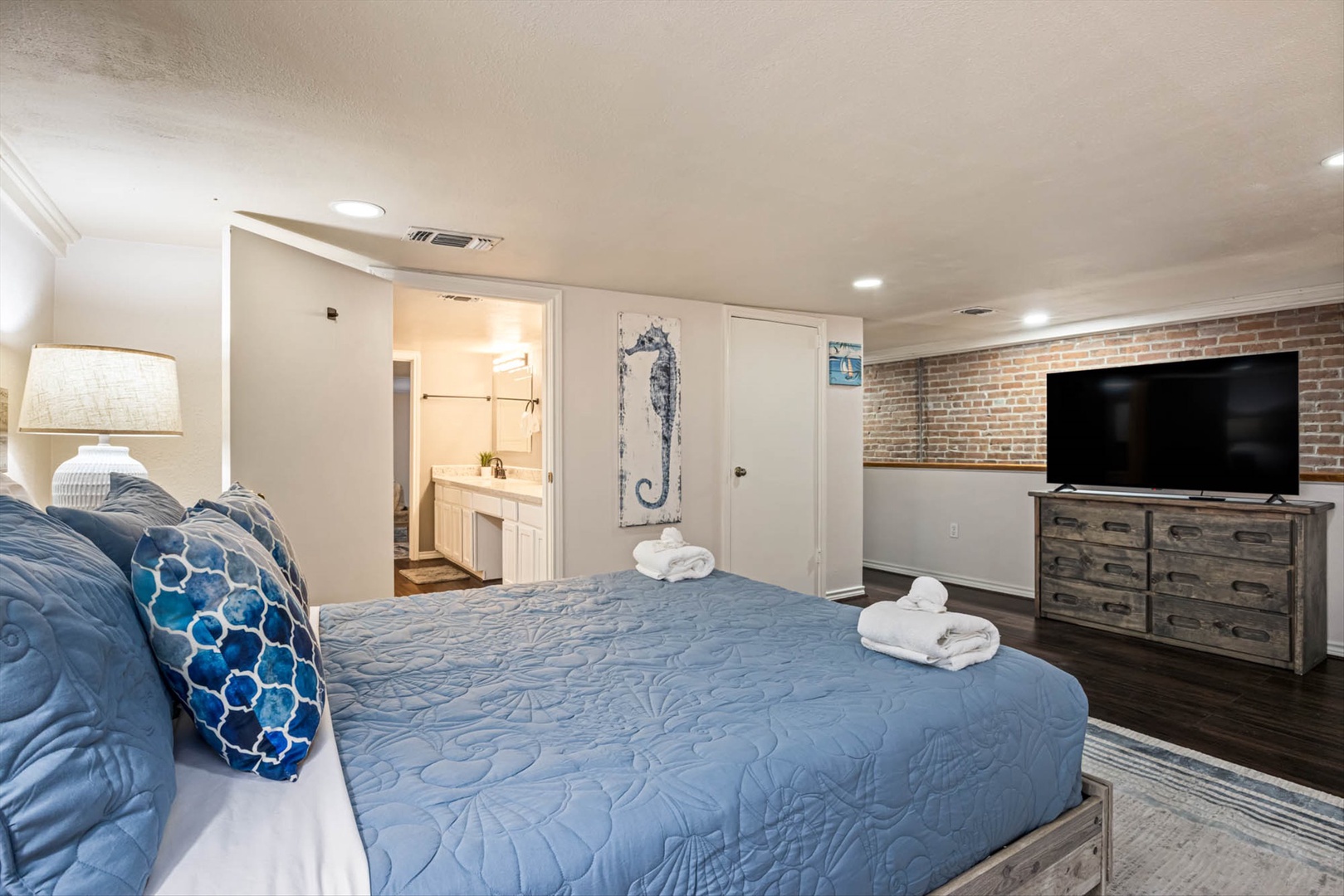 Cozy bedroom with ocean bedding, TV, and en-suite bathroom.