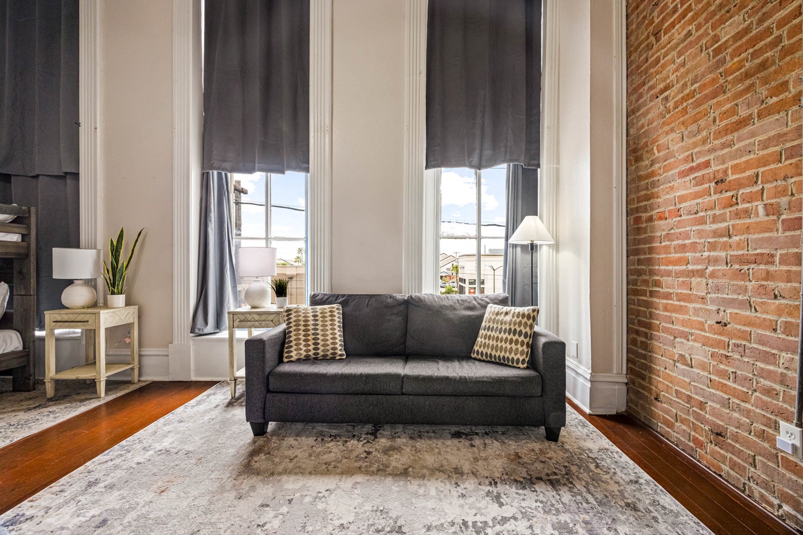 Urban living space with brick walls, seating, and tall windows.