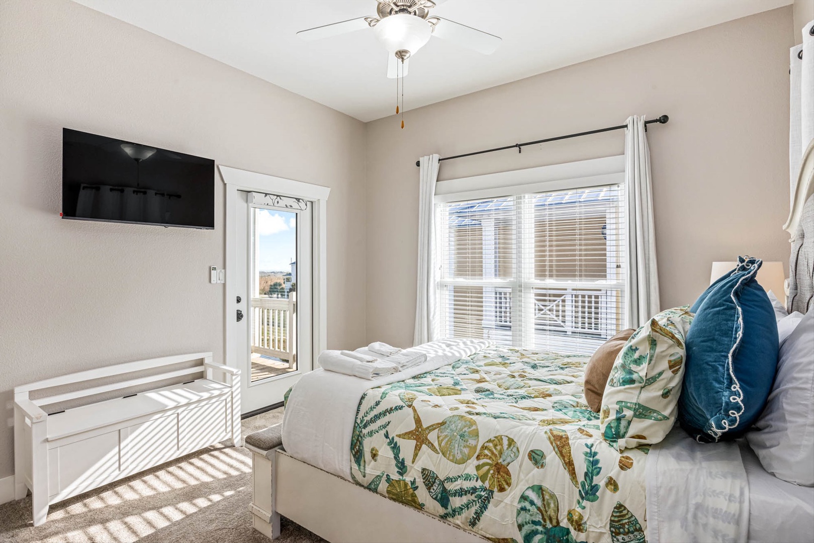 Upstairs bedroom with ocean décor, TV, and private balcony.