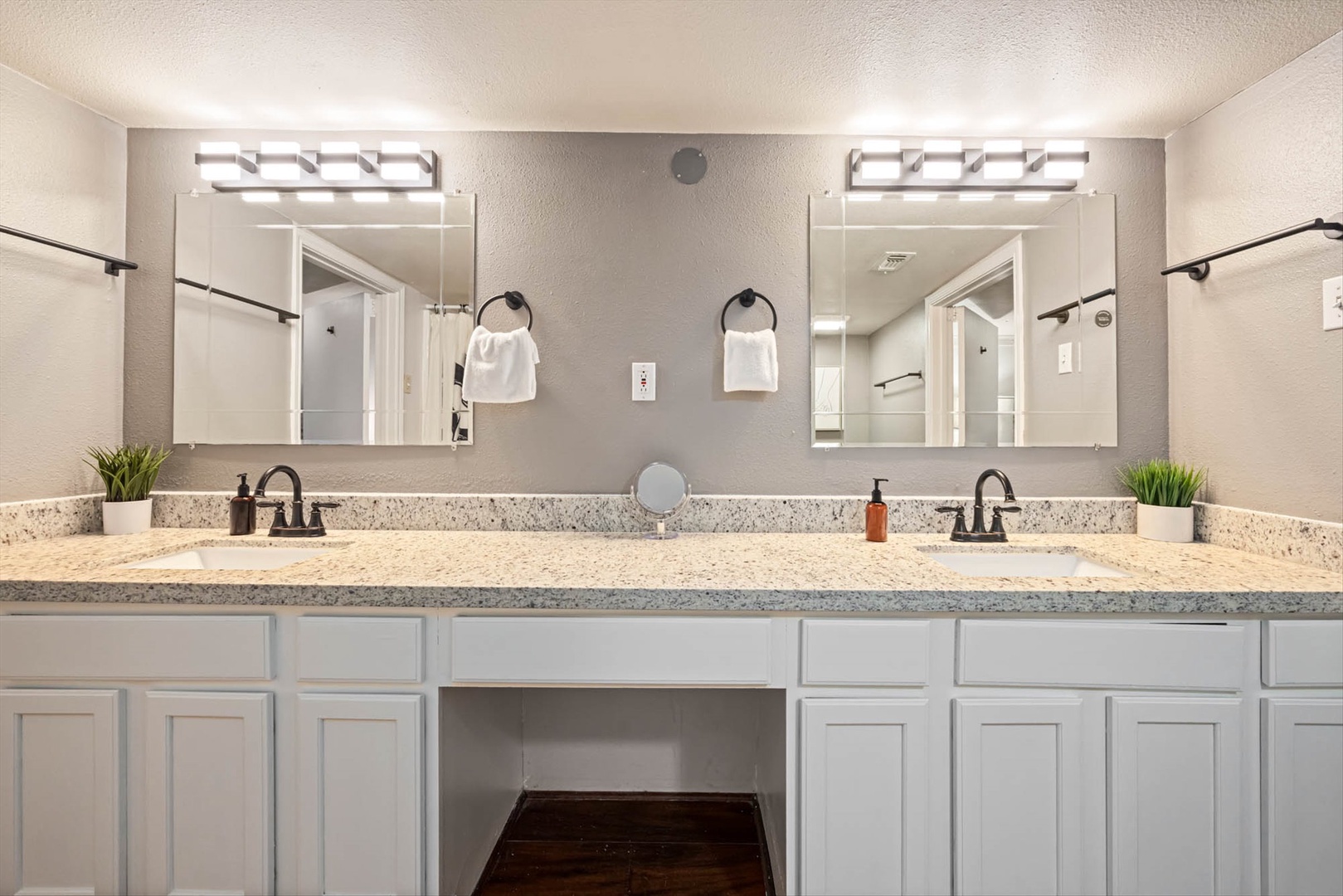 Modern dual-vanity bathroom with granite counters and plants.