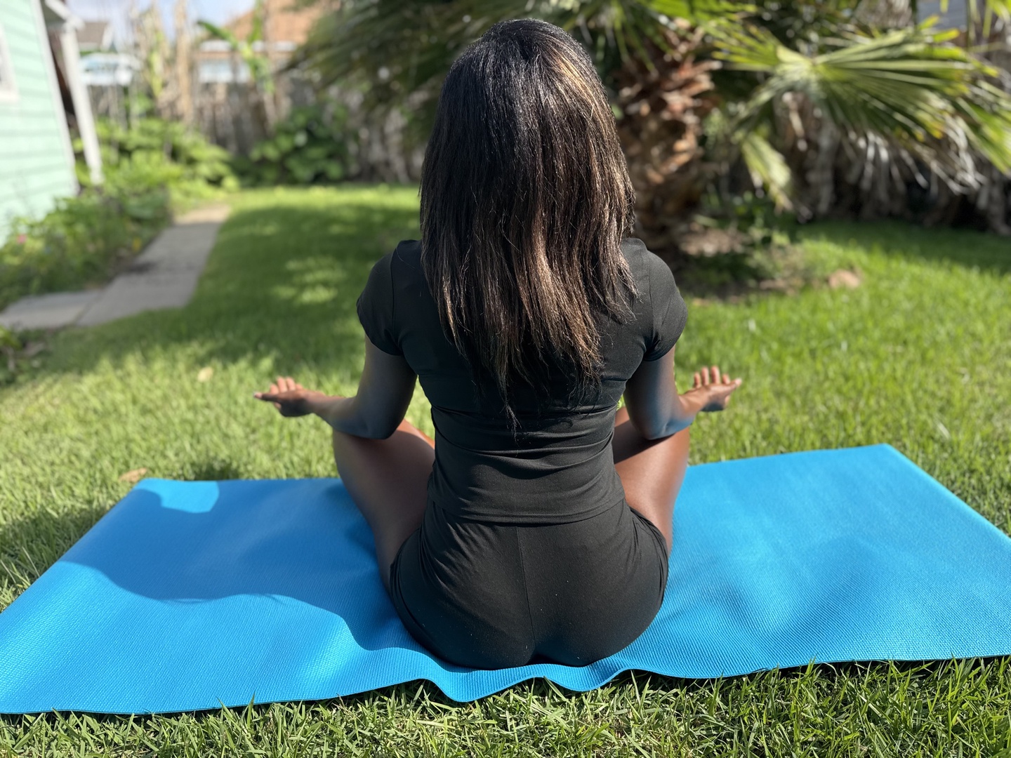 Meditate in the peaceful garden beside lush greenery and tropical palms, where calm turquoise waters shimmer in the background. Find your inner stillness here.