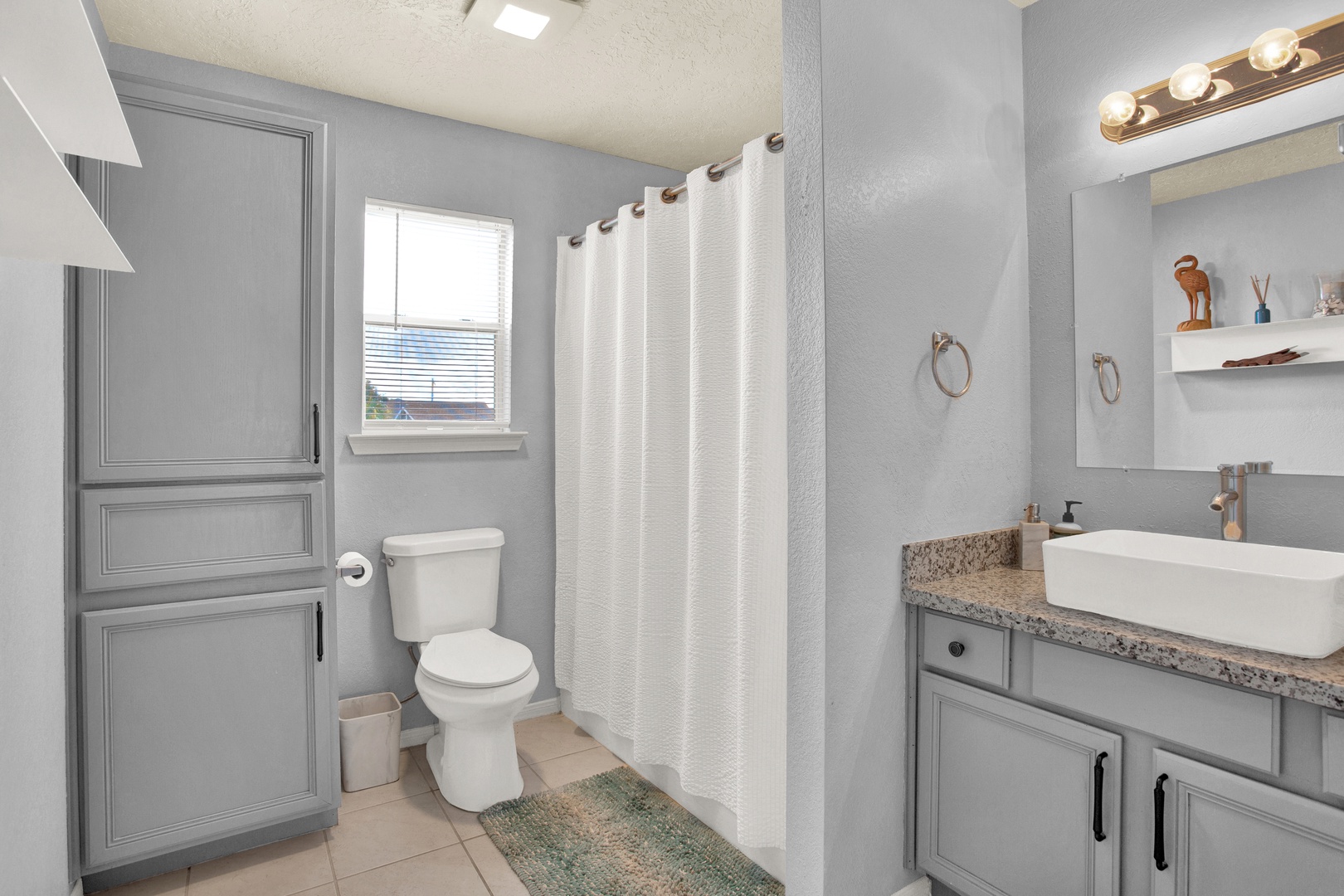 Step into your serene gray-toned bathroom with modern fixtures, a spacious vanity with vessel sink, and a soft shower curtain that creates a calming retreat after your day exploring.