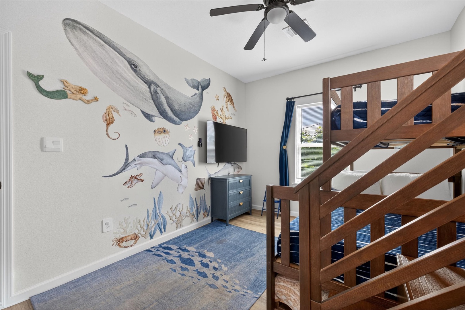 Underwater-themed kids’ room with bunk bed and TV.