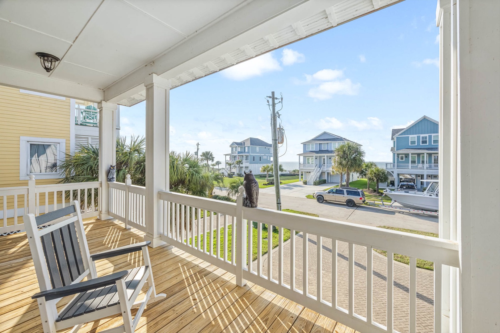 Covered porch at front door with rocking chairs and coastal views.