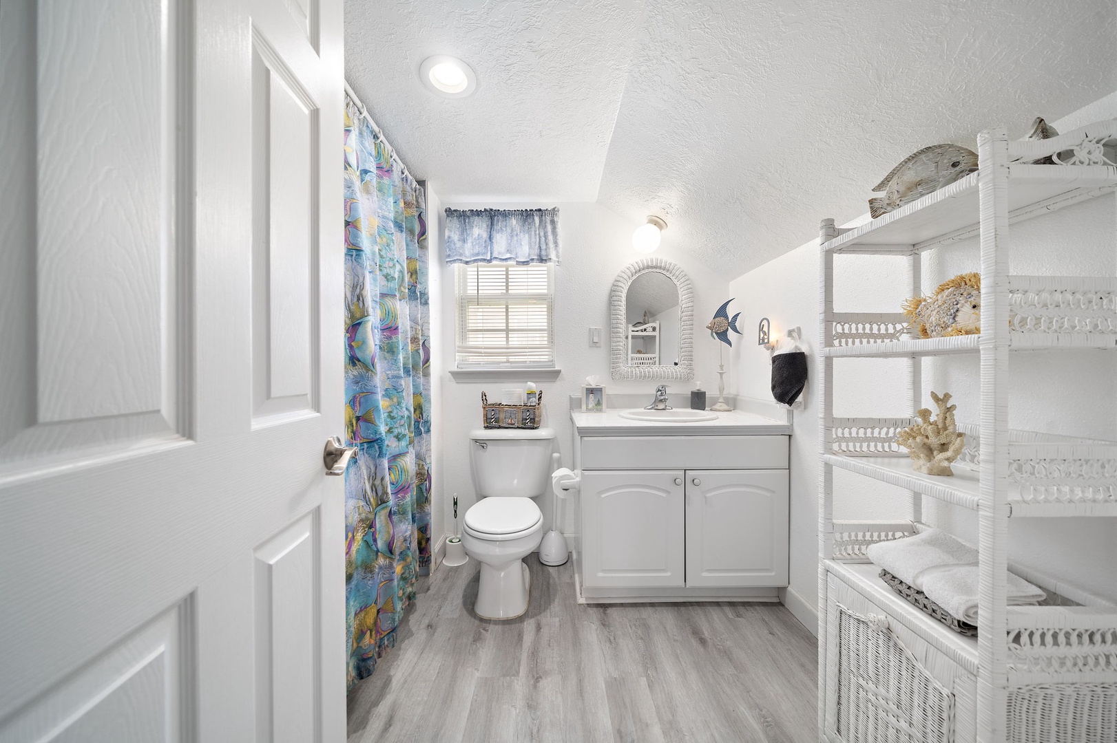 Step into your bright, organized upstairs bathroom where every detail adds comfort to your stay. The cheerful ocean-themed shower curtain and thoughtful storage make this space feel like home.