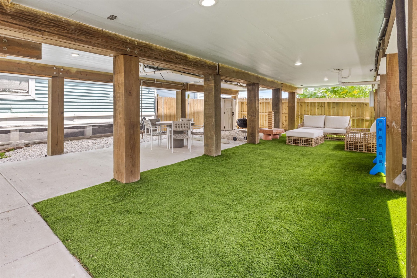 Outdoor covered space with turf and relaxing seating.