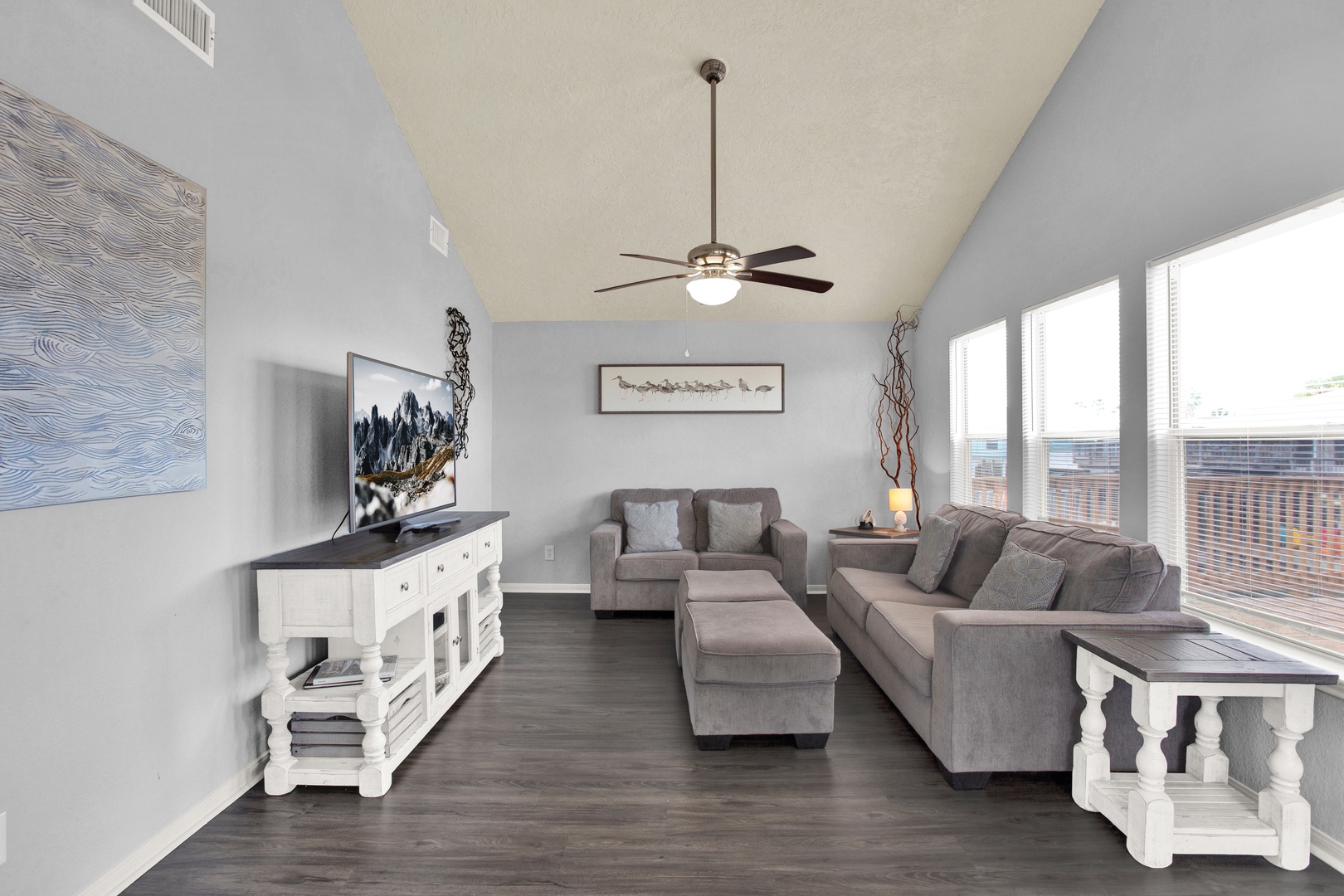 Settle into plush gray sofas in your bright living room, where vaulted ceilings and soft natural light create an airy, welcoming retreat after your day of exploring.