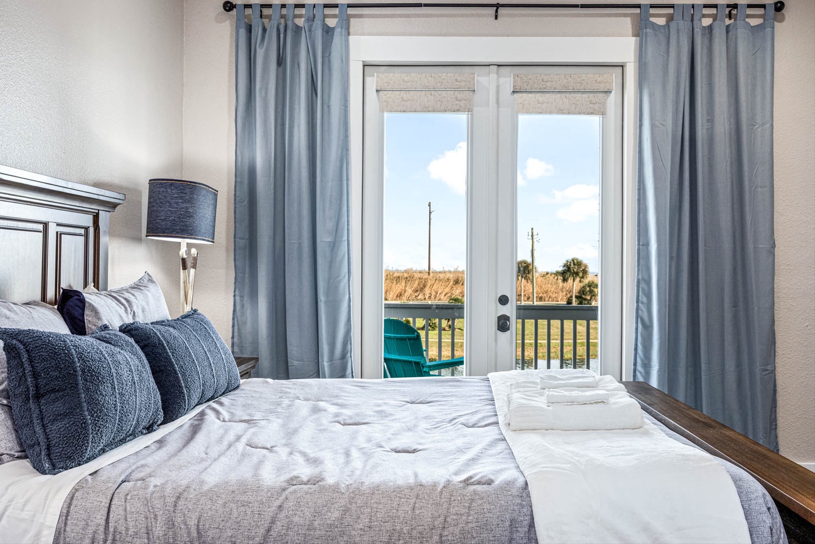 Coastal bedroom with balcony overlooking serene marshlands.