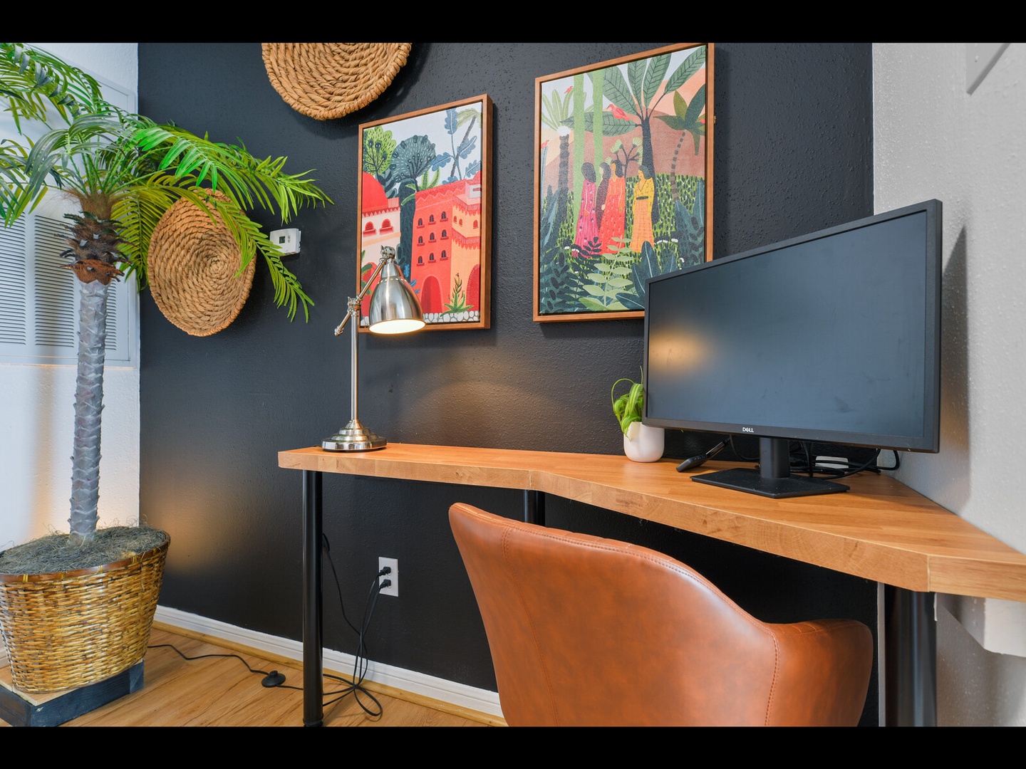 Stylish workspace with desk, chair & tropical art