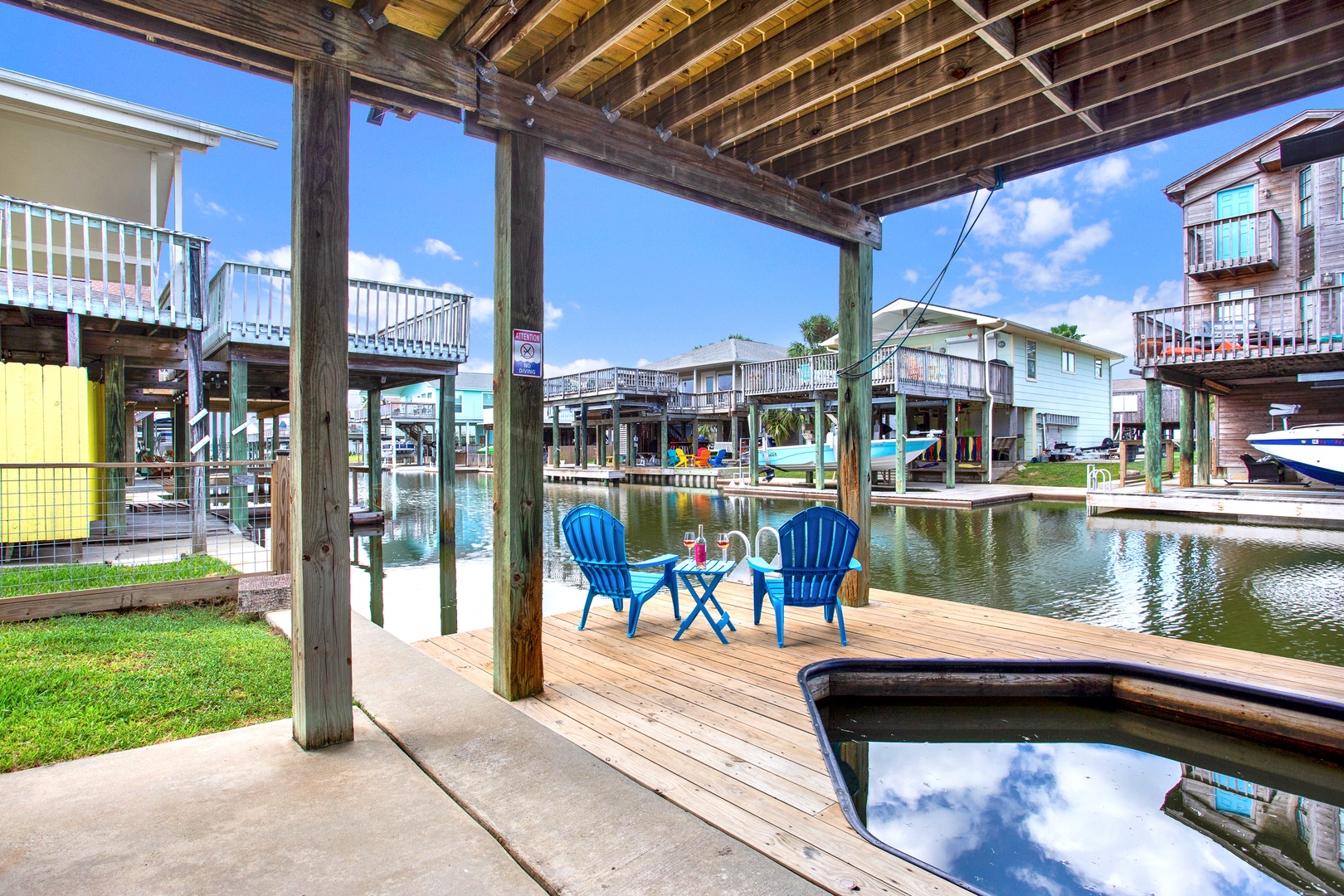 Covered deck overlooking a tranquil canal in a waterfront community. Kick back in the bright blue chairs and enjoy peaceful waterside living surrounded by colorful beach homes and private docks.