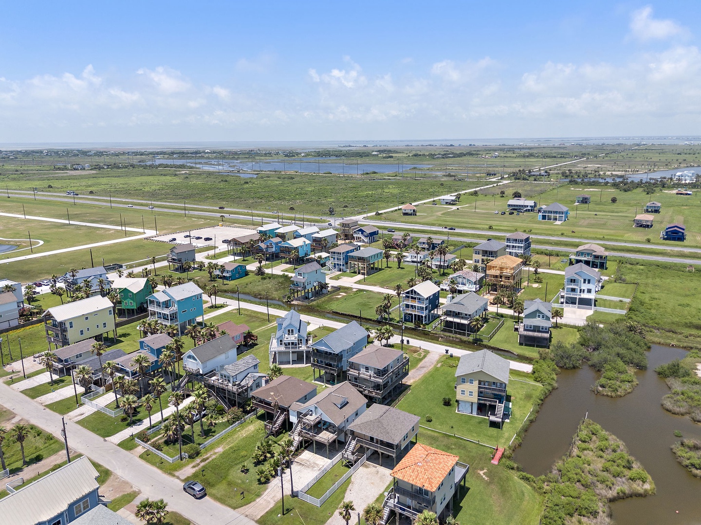 Your coastal getaway awaits in this charming beachside community! You'll love the colorful elevated homes scattered across the green landscape, with scenic waterways and open skies creating the perfect backdrop for your vacation.
