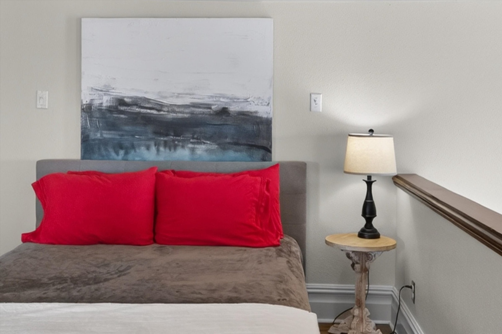 Bedroom with red pillows, soft bedding, and warm lighting.
