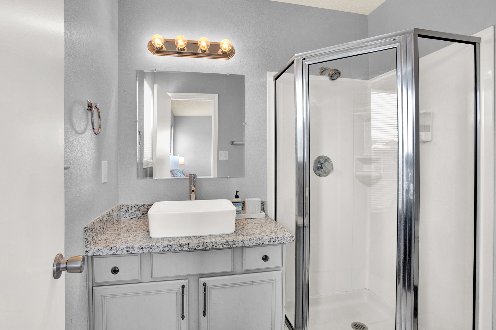 Step into your spa-like bathroom with its clean lines and modern fixtures. The walk-in shower and vessel sink provide a refreshing start to your day, while warm vanity lighting creates a welcoming ambiance.
