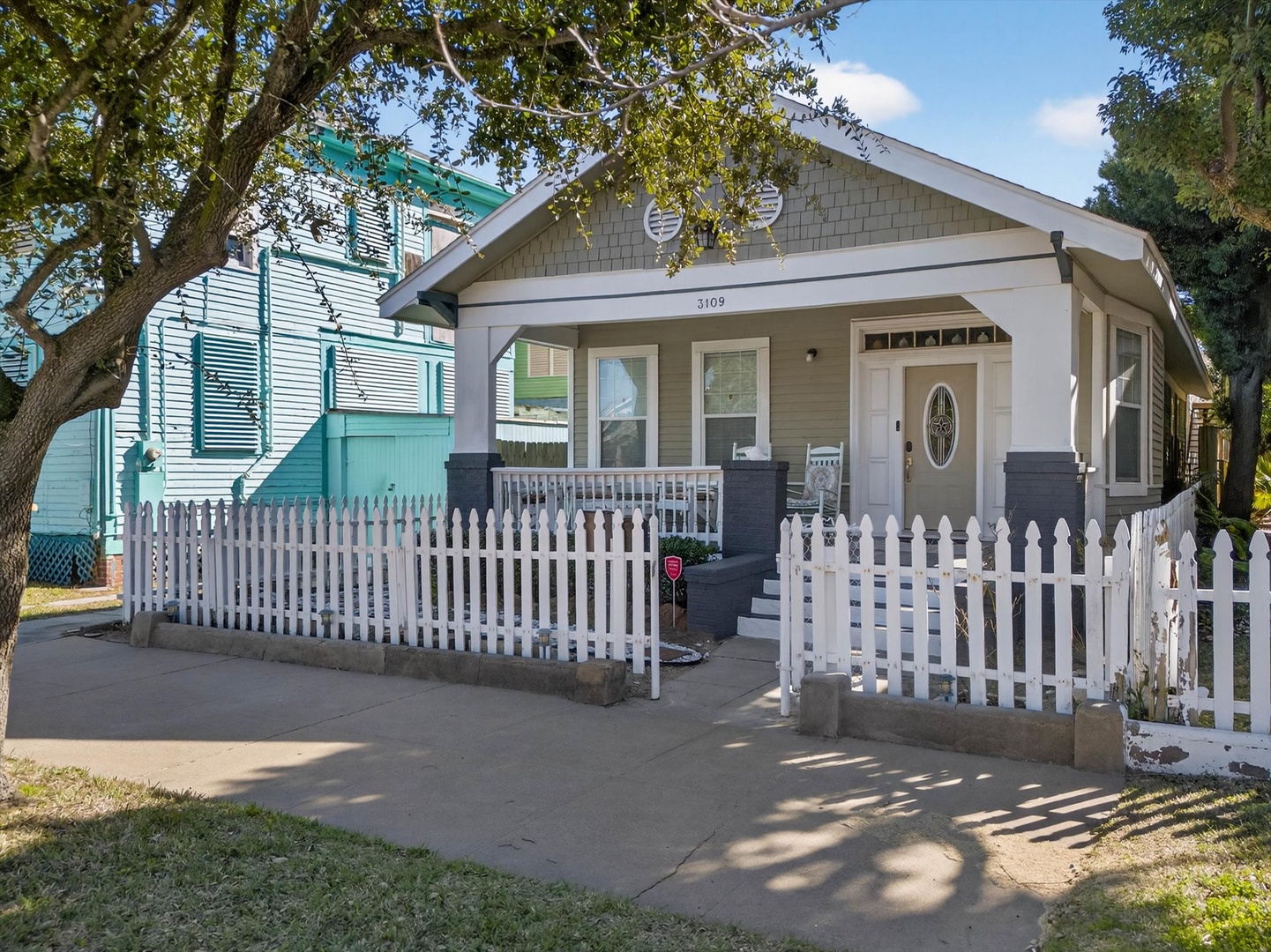 Charming craftsman-style home with classic white picket fence and welcoming front porch in a tree-lined neighborhood.