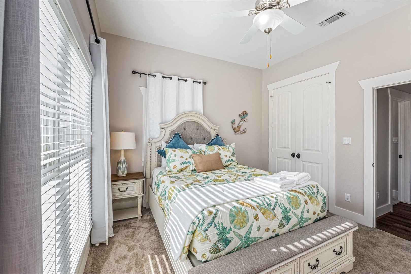 Upstairs coastal bedroom with tropical linens and fan breeze.