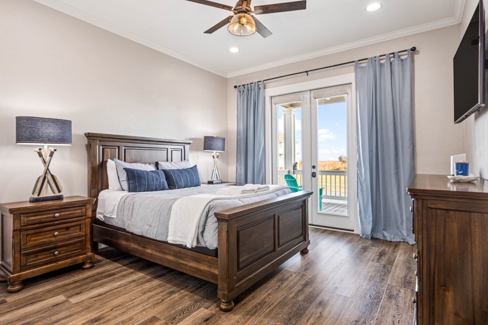 Bedroom with French doors, balcony, and water and beach views.