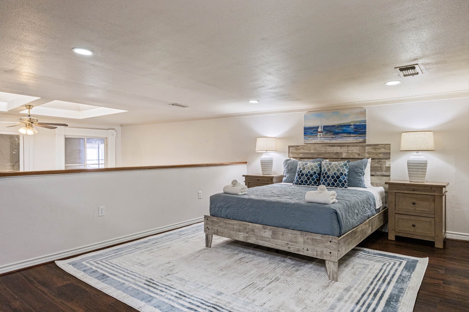 Rustic wooden bed with coastal linens in a spacious bedroom.