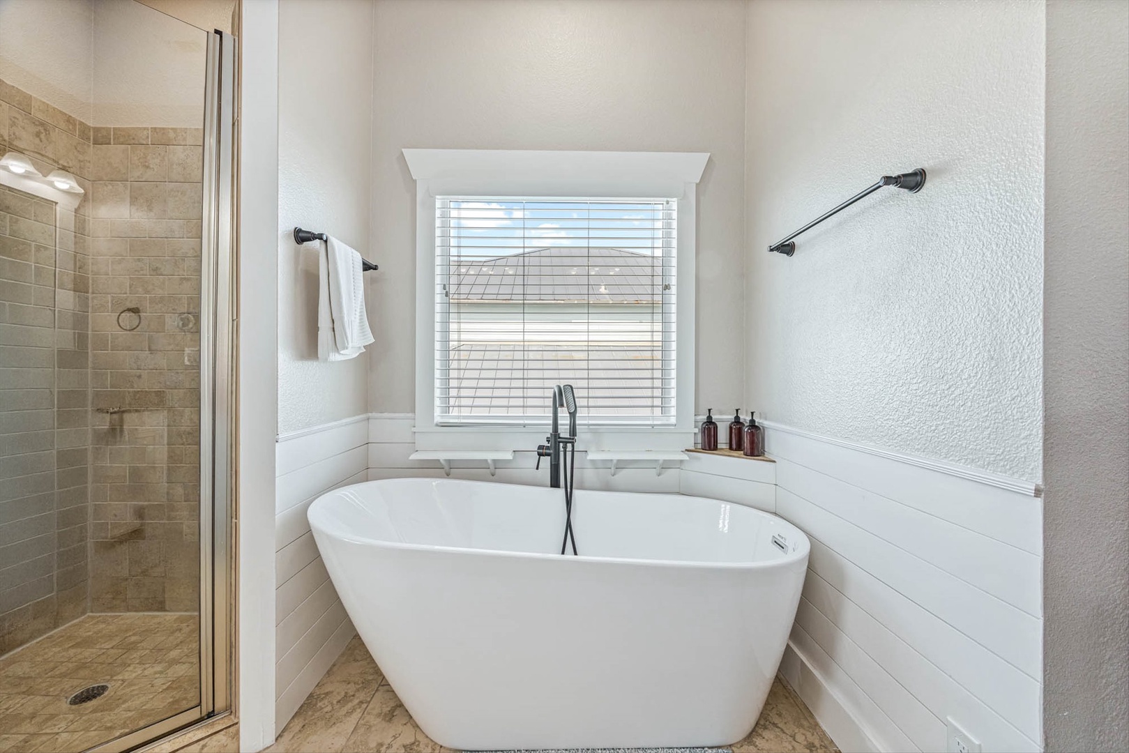 Elegant soaking tub with natural light and spa toiletries.