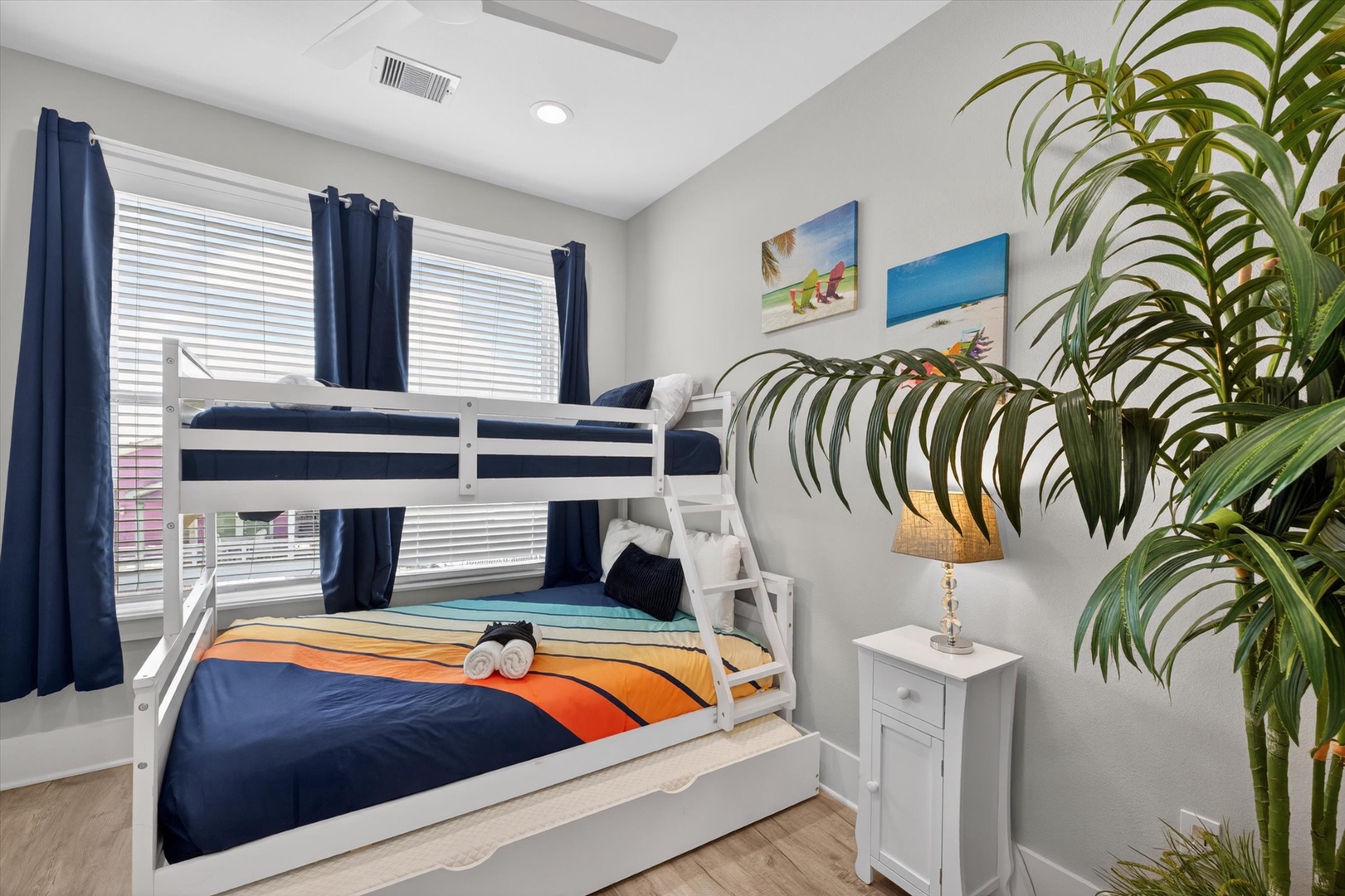 Coastal bunk room with beach art and colorful bedding.