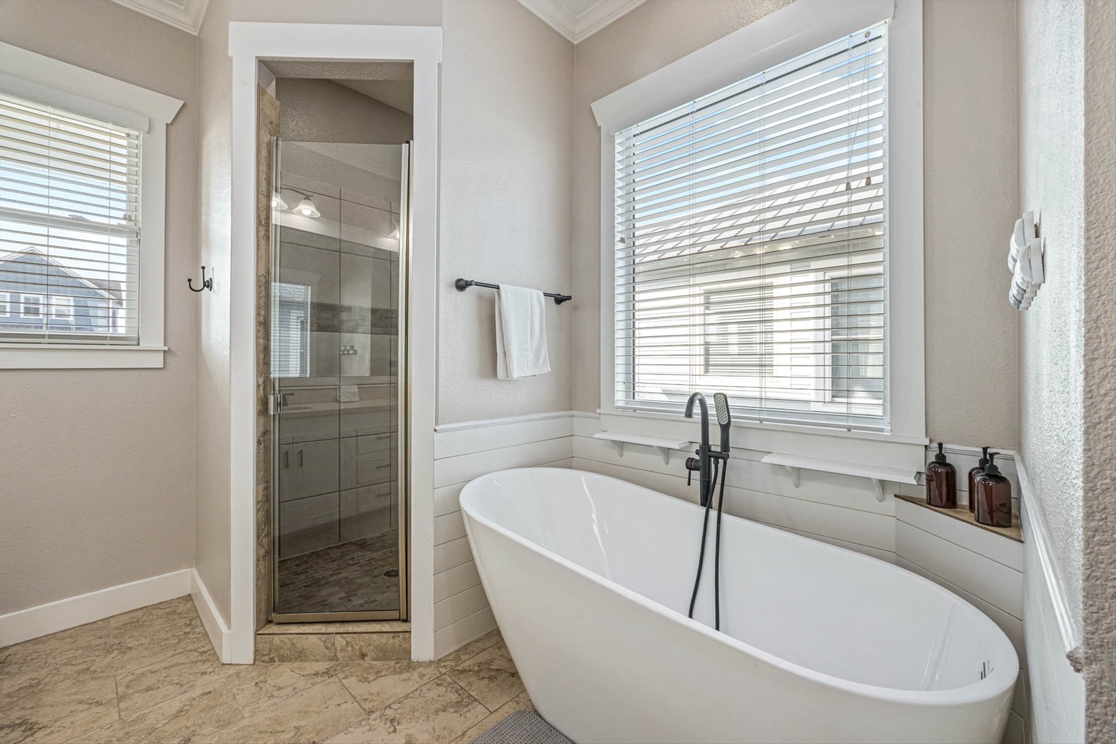 Luxurious bathroom with tub, glass shower, and natural light.