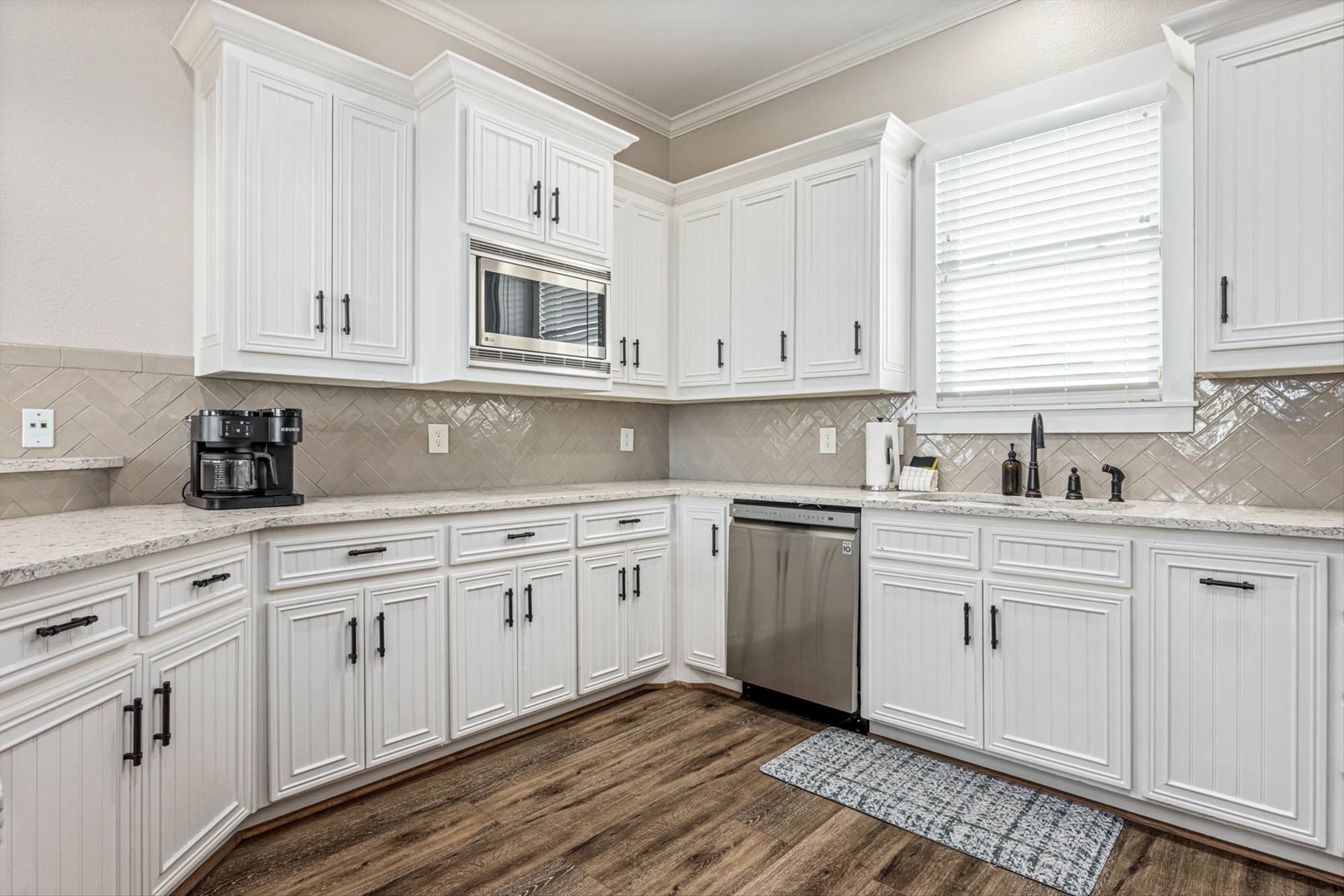 Modern kitchen with white cabinets and granite countertops.