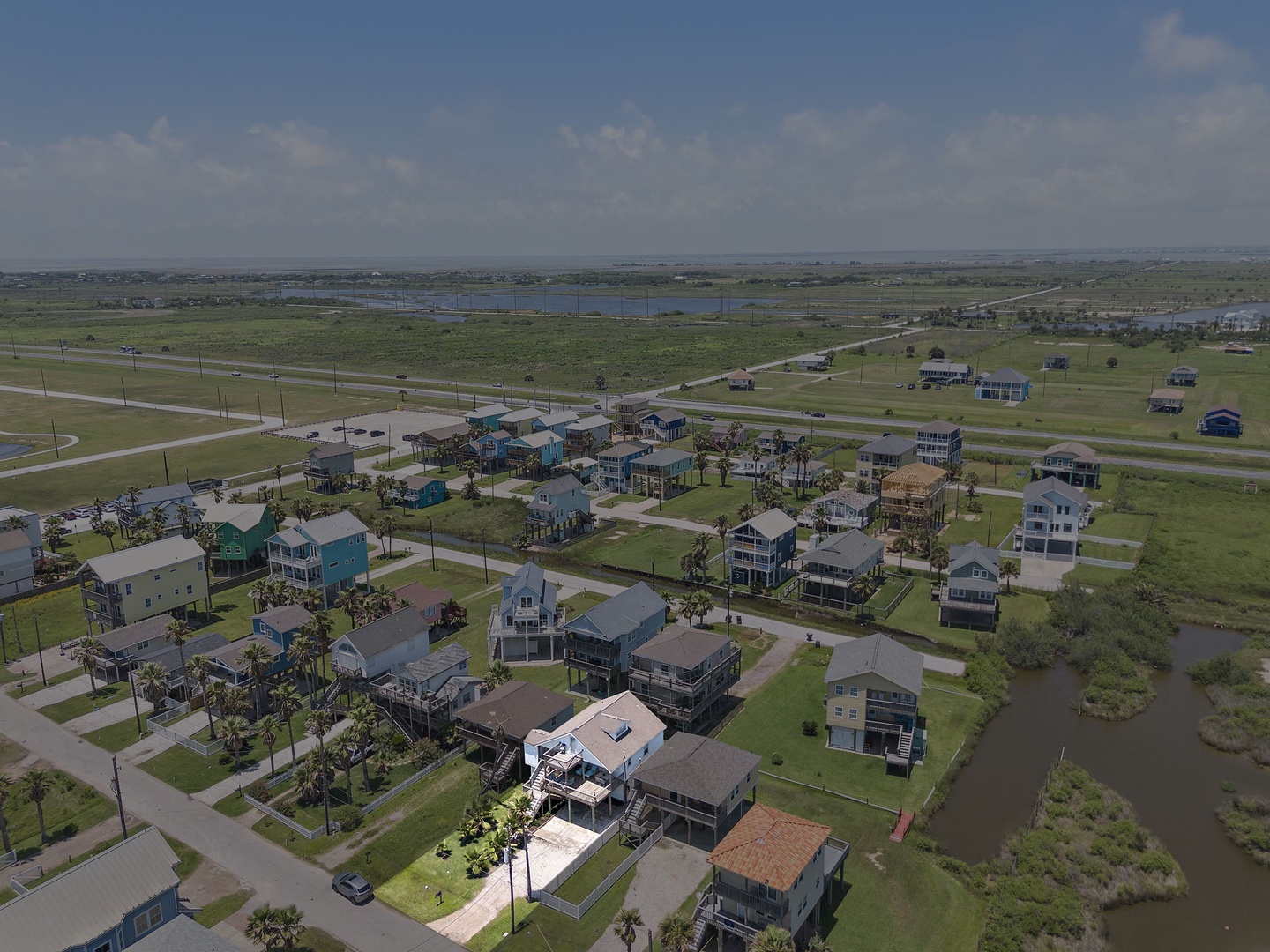 Soar above your coastal getaway and take in the breathtaking bird's-eye view of this charming beach community. Watch as colorful vacation homes dot the landscape beneath endless blue skies, promising your perfect escape.