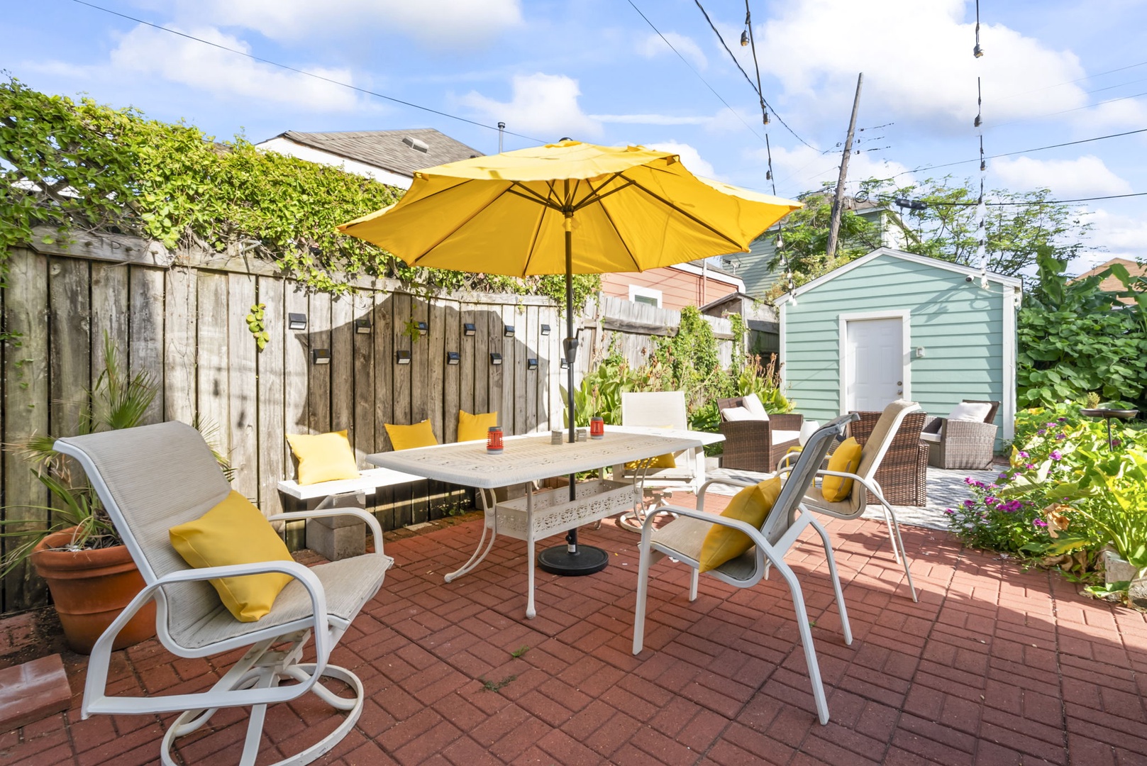 Outdoor dining patio with umbrella and garden surroundings.