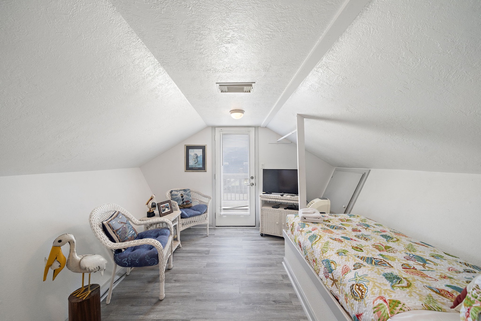 Your cozy attic retreat awaits with charming sloped ceilings and peaceful white-washed walls. Sink into the wicker seating while enjoying your private balcony access and entertainment center.